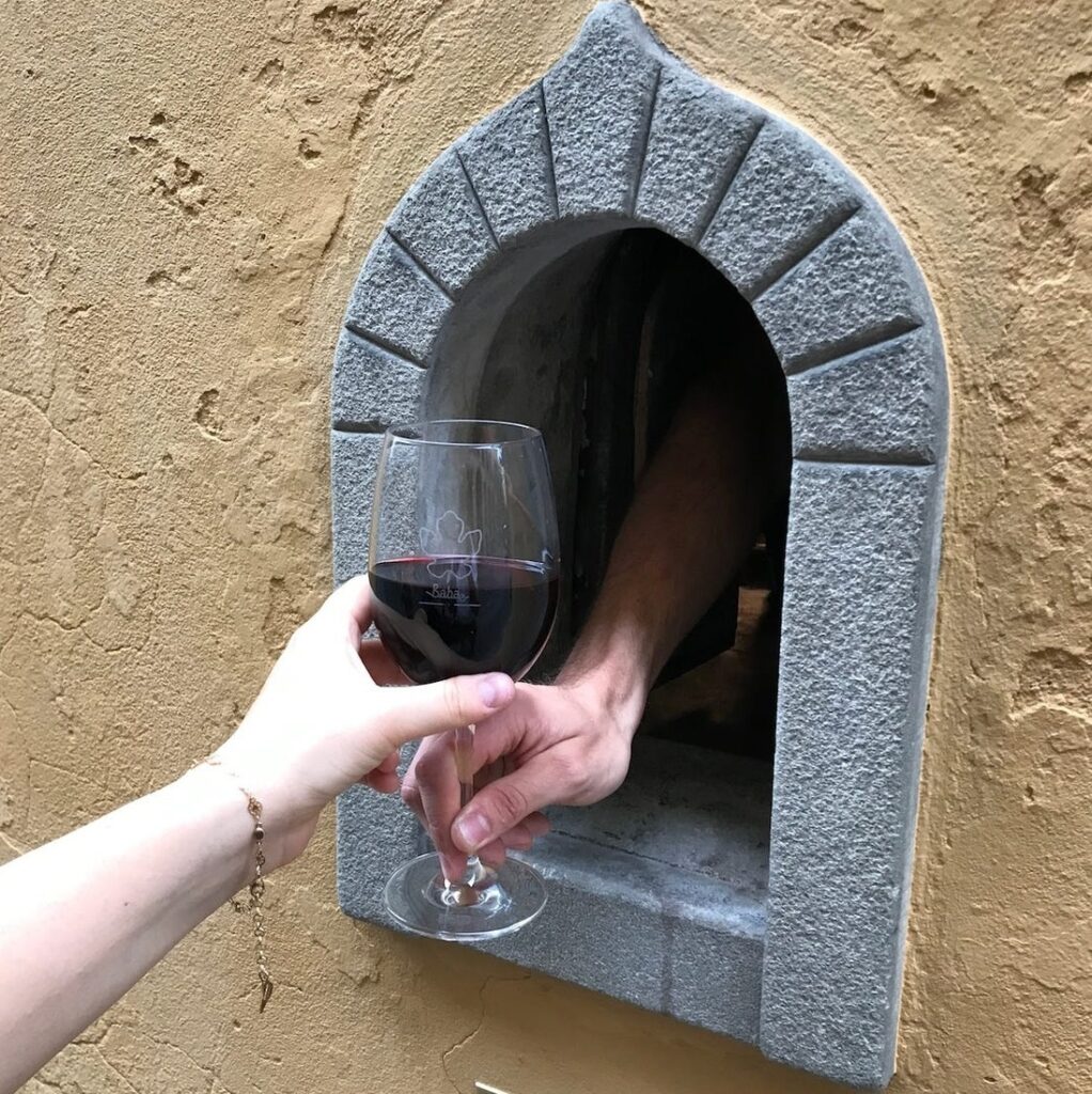 Uma mão recebendo um vinho através da janela de vinho